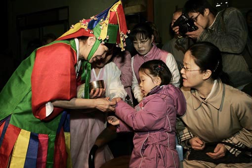 작두에서 내려온 만신은 사람들에게 공수와 함께 복쌀을 나눠준다. 어린이가 고사리 손으로 복쌀을 받는 모습이 앙증맞다. 이때 만신은 그녀 가슴에 묻은 아들을 생각하고 있었을까? 